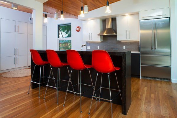 The renovation also included a completely new open kitchen with Italian-inspired cabinets, sleek hardware and bare bulb pendant lights, which replaced the existing galley kitchen. By removing the existing wall, the kitchen now opens up to the dining room. Removing the wall opened up all three rooms (living, dining, kitchen) and connected them to one another. Photo 2 of Highland Park Residence modern home