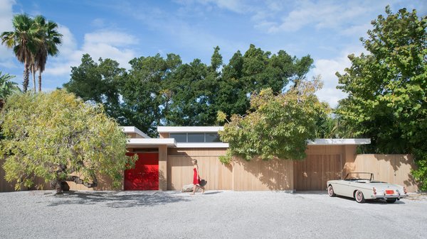 The Pavilion House's outer wall encircles a snaking courtyard that connects many of the home's interior spaces. After a step inside the lipstick red door, guests are greeted with an entrance into the home's exterior or to private patio on the left. Within that outer wall, both indoor and outdoor spaces appear to be one in the same. Photo of The Pavilion House modern home