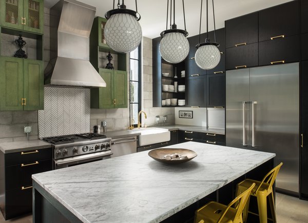 Modern home with kitchen, marble counter, wood cabinet, dark hardwood floor, concrete counter, subway tile backsplashe, pendant lighting, concrete backsplashe, range, range hood, dishwasher, and refrigerator. The kitchen is the heart of the home, and its design was carefully appointed with craftwork by local artisans. Brass pulls were custom designed and crafted to suit the space. The metal mesh on the upper cabinets was replicated with milled details in the cabinets beneath them. Concrete and marble counter tops provided a solid balance of industrial design and luxury. Photo 9 of 400SOLA