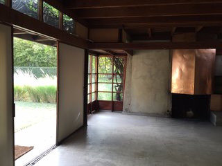 Schindler found inspiration in Japanese screens to help create indoor-outdoor movement in the house. On the right is a custom copper mantle over a simple fireplace.