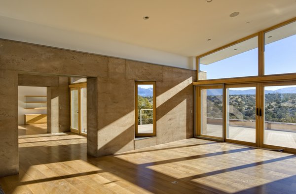 The home’s materials and colors were drawn specifically from the site to help it meld into the landscape. It is a custom rammed earth house. Rammed earth is an ancient process originating in the Middle East inspired by a desire to be one with nature. It is a style and building technique that is true to the region, the foundation of the adobe construction that is popular in Santa Fe and surrounding regions. The masonry of the project makes it unique: it was carefully crafted to maximize and adapt to the varying temperatures in the region, allowing for comfortable interior temperatures. Photo of La Tierra Nueva modern home