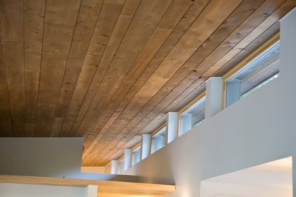 Modern home with windows and wood. The home seamlessly integrates a floating cedar tongue and groove roof with large sheltering overhangs, clerestory windows, and language of cedar slats for privacy screens and doors inside and out. The tops of these windows reveal the interior cedar clad and the up-swept soffits on the home’s exterior, creating a floating ceiling effect. Photo 10 of Cedar Haus