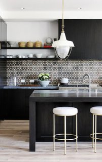 10 Open Kitchen Solutions That Will Get Things Cooking - Photo 10 of 10 - In this kitchen by DISC Interiors, the stark black cabinets and kitchen island are offset by light whitewashed floors and white-and-brass accents. To finish off the look, a patterned ceramic tile backsplash packs a punch. 