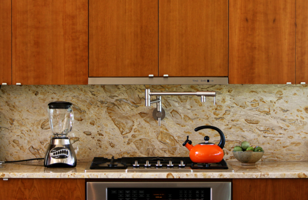 The kitchen was designed to be as sleek and minimalist as possible, yet remain "warm" to the eye. Unlike a range, a cooktop and oven do not disrupt the line of the countertop. The range hood is mostly hidden and only shows a thin horizontal line tucked within the line of the cabinets. It pulls out when in use, and slips back into line with the cabinets when not. Photo 8 of The Goat Sheds modern home