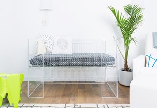 15 Modern and Creative Spaces For Kids - Photo 7 of 15 - Little Crown Interiors inserted a transparent crib into this Los Angeles nursery—along with a clear changing table and side table. Pops of green and blue almost glow in comparison to the transparent surfaces.