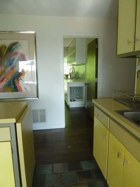The new laundry/pantry/dog room was constructed in a small bedroom located directly across the hall from the kitchen. Because the original kitchen is fitted with custom cabinetry, finished in four shades of greens and yellows, I decided to keep the laundry neutral. A green glass mosaic tile backsplash was added to add a splash of color and tie the laundry into the kitchen. Photo of Modern Laundry, Pantry and Dog Room modern home