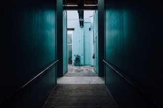 Peering down a dark hallway into cerulean blue green.