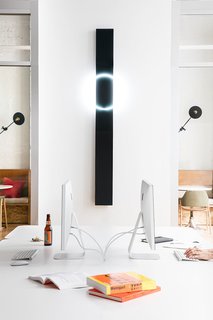 Large white desk space is set against dark and neon wall art with accents of plywood.