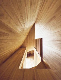 The Community-Run Cedar House by Airbnb and Go Hasegawa Welcomes Guests in Rural Japan - Photo 11 of 12 - Looking down the stairway from above reveals another view of the "A" shape of the upper floor with contrasting angles created by light and shadow.