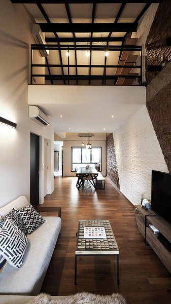 The open concept (the dining and living area). The clean white streak across the original pre-war brick wall gives the room a certain edge and modernity, blending old and new.
The coffee table has a rich history - the table top was a gem found in a vintage Danish store; it used to be used by a printing company in Denmark, to store the letterings. Metal legs were then customised for it to rest on, repurposing the letter-holder into a perfect coffee table. The owners love items with a story to tell. Photo 18 of The Singapore Designer Loft: A Fusion of Old and New modern home