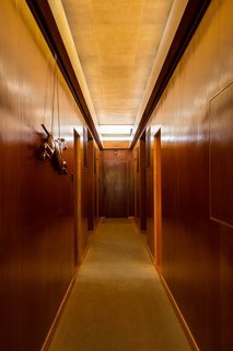 What Would Victor Do? - Photo 5 of 11 - A long clerestory illuminates the hallway dividing the bedroom<br>wing of the house. The door at the end originally opened to racquet storage and<br>pathway access to a subterranean tennis court. The carved greyhound dates to<br>the 1920s.
