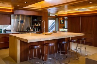 What Would Victor Do? - Photo 6 of 11 - The renovated kitchen honors architectural precedents<br>in the house, including lighting coves, crescent<br>drawer pulls, and match-grained cabinetry doors<br>that roll along the same hardware used in 1947. The<br>clerestory directs light onto the maple island, whose<br>proportions and structure pay homage to the dining<br>room’s original table. Even the terrazzo recalls the<br>feeling of the first flooring material—asbestos tile—<br>which was abated for safety. 