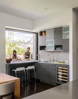 A pocket window in the kitchen allows for a double-sided bar area, with access to the outside grill. "It’s a great place to sit and drink your morning coffee and enjoy the views," said Goff, who placed two Tiffany counter stools at the pass-through bar. The kitchen cabinets are a mixture of rift-cut white oak and cabinets painted in Benjamin Moore’s low-gloss Iron Mountain hue, with Caesarstone countertops. 