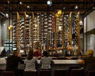 Illuminating Atmosphere With 111 Bocci Lights - Photo 3 of 7 - The two story wine rack at Il Posto serves as a focal point within the space. It also functions as a screen between diners and the kitchen. Guests are afforded multiple views of the towering piece as the stair to the mezzanine slides behind the rack and moves through the space. 