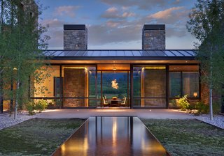 Naturally Modern - Photo 13 of 15 - CRESCENT H – Situated on top of a sloping knoll and an aspen grove, this home was sited to capture panoramic mountain views and create a dramatic arrival sequence. The program is arranged in separate building forms to cultivate intimacy while maximizing exposure. Movement is choreographed to contrast solid characteristics with void, creating pockets of shelter and outdoor connections. The roof protecting the kitchen pavilion, along with the kitchen and dining rooms, lays across an east-west axis to take full advantage of the scenery. Sedimentary stone from a nearby quarry mimics the natural landscape, with clear vertical grain cedar siding to break up the pattern and add warmth. Photo by Gibeon Photography.