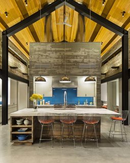 A Yurt-Inspired Vacation Home on the High Desert Plains of Colorado - Photo 5 of 8 - The cathedral-shaped steel beams outline the open plan of the main house, which includes a kitchen, upstairs loft, bathrooms, and hallways that connect all of the yurt structures. The central structure is made of concrete and serves as a thermal mass to keep the home cool in summer and warm in winter.