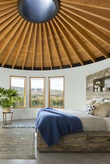 A Yurt-Inspired Vacation Home on the High Desert Plains of Colorado - Photo 4 of 8 - The ceiling of all three yurts is made with tongue-and-groove planks of Douglas fir that meet at a steel skylight at the center. A custom-made bed is complete with a linen duvet cover from Coyuchi and enticing sheepskin pillows.