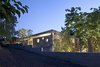 Modern home with Side Yard, Trees, Exterior, Concrete Siding Material, Wood Siding Material, and House. This home took inspiration from the brutalist buildings found in its Tel Aviv neighborhood. The home is comprised of two concrete squares stacked on top of each other, with a skylight running along the entire length of the stairwell and flooding the home with sunshine. Sections of the silicate-brick walls have circular holes cut out from them in order to connect the various rooms visually. Photo 13 of House of an Architect