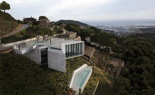 Located just outside of Barcelona and sited on a steep hill overlooking a valley and the Mediterranean Sea, X-House by Spanish architectural studio Cadaval & Sola-Morales has bold, fully-glazed angled frontages that look out to stunning views of the surrounding landscape. 