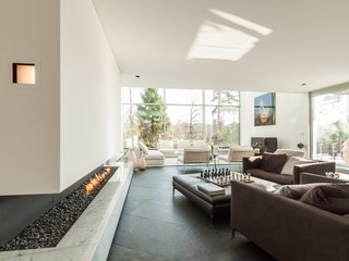 This six-bedroom villa in Brussels has a cut-in-stone fireplace underneath a glass-enclosed walkway.