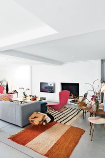 The discreet fireplace in this Belgium home blends in with the wall-mounted television, Low Pad chair by Jasper Morrison, and a brass-and-steel coffee table in the cozy living room.
