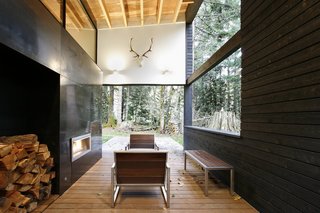 In Greenwater, Washington, a courtyard house on a river was designed with a steel-clad fireplace mass that separates the living room from a covered outdoor patio. 