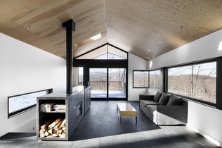 In this home in the snowy forests of Eastern Quebec, a centralized fireplace was built into a custom, multi-purpose cabinet welded from sheets of hot-rolled steel. 