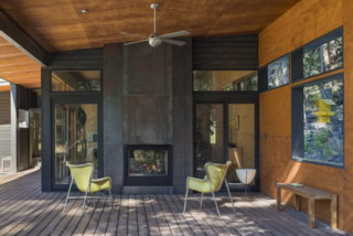 A modern cabin in Washington’s Methow Valley has a fireplace with glazing on two opposite sides, so its owners can watch the embers of the fireplace glowing either while sitting out on the patio, or from the lounge area within.
