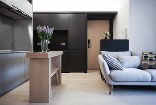 10 Small Apartments by a Hong Kong Design Studio That Are Less Than 1,000 Square Feet - Photo 6 of 10 - A fuss-free monochromatic color palette works beautifully with unvarnished wooden floors, blown-glass pendants, and sleek stainless-steel kitchen counters. A slim wooden island counter with just enough space for an elongated bench serves as a food preparation area and doubles up as a tiny dining table. 