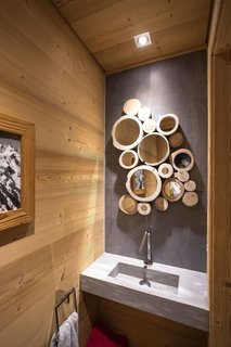 8 Structures and Spaces That Use Mirrored or Reflective Surfaces in Interesting Ways - Photo 4 of 8 - Nature is present throughout the interiors of this French Alpine home, including in the bathroom, where the cross section of tree trunks serve as frames in a cluster of small mirrors. 