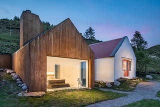 9 Traditional-Turned-Modern Cottages You Can Rent in the UK - Photo 7 of 9 - This quaint cottage near the remote lakeside town of Treangarriv in County Kerry has a poured-concrete extension that mimics the original adjoined cottage. The color of the wood grain and oxidized concrete match the mountains in the background and helps the extension blend seamlessly into the landscape. The bathroom has a glass roof so that guests can gaze up at the stars from a sunken bathtub.