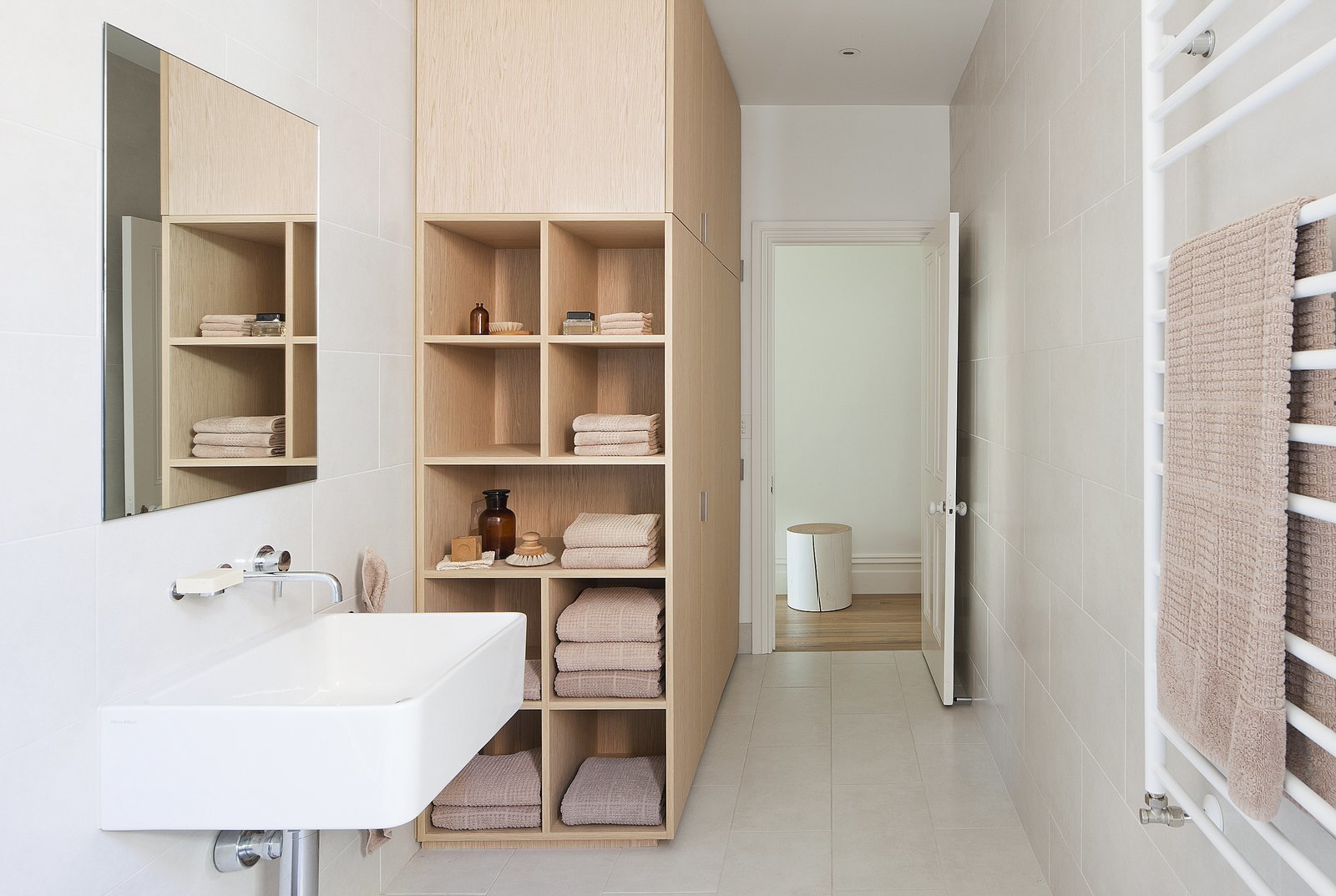 This home in Melbourne by design duo Kathryn Robson and Susie Cohen has deep nook shelves at one end of the wardrobe, which gives the bathroom a warm, natural and organic feel.