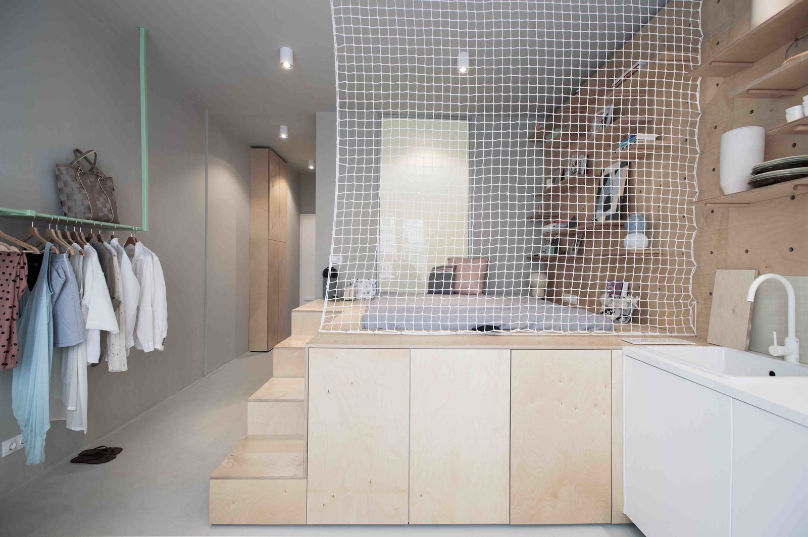 To maximize space in this tiny 323-square-foot studio Budapest apartment, local design studio POSITION Collective used an elevated, plywood sleeping unit inspired by Japanese “tansu” mobile cabinetry, with secrete storage modules on the side of the steps leading up to the futon bed.