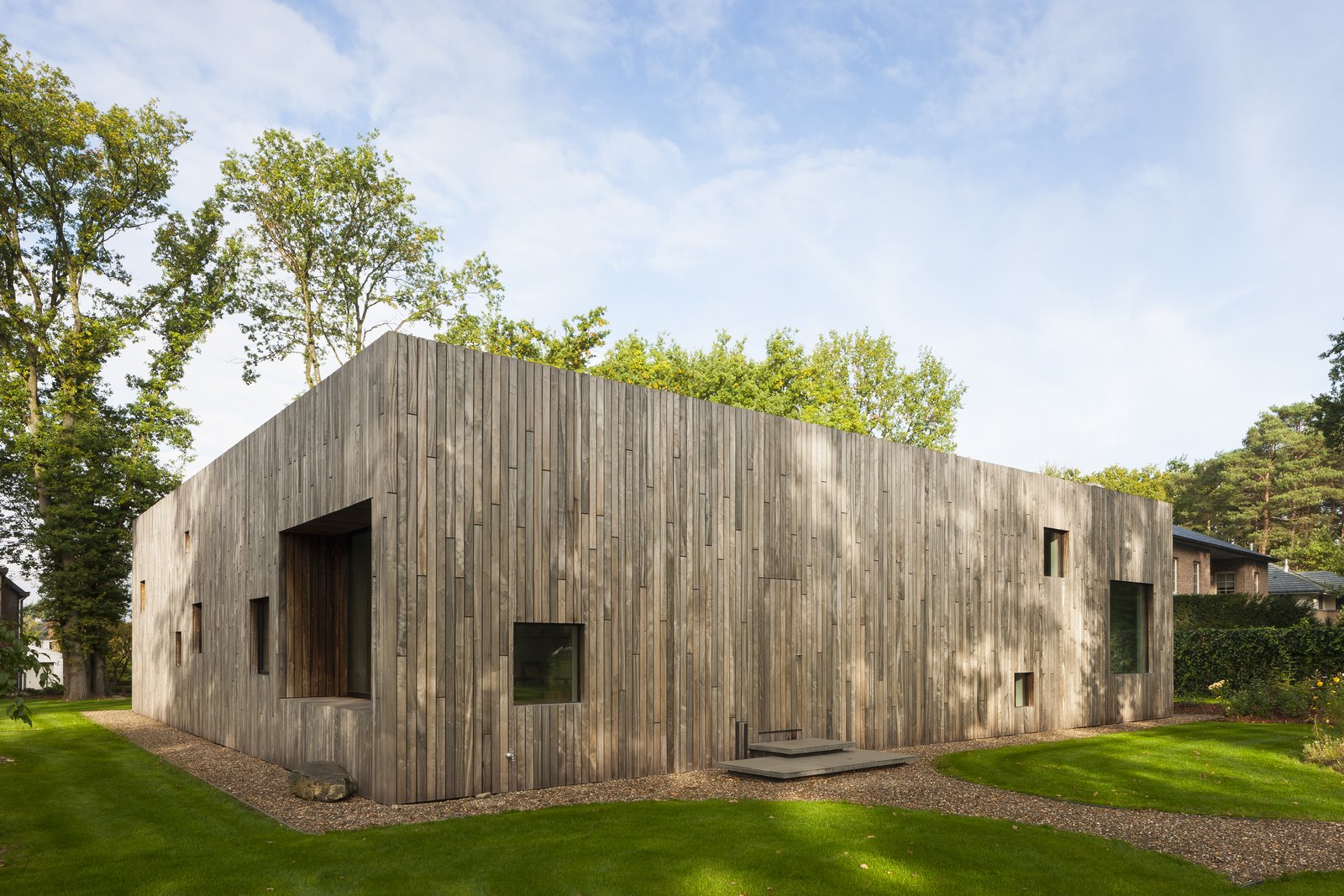 Several square perforations of varied sizes along wooden facade serve as windows.