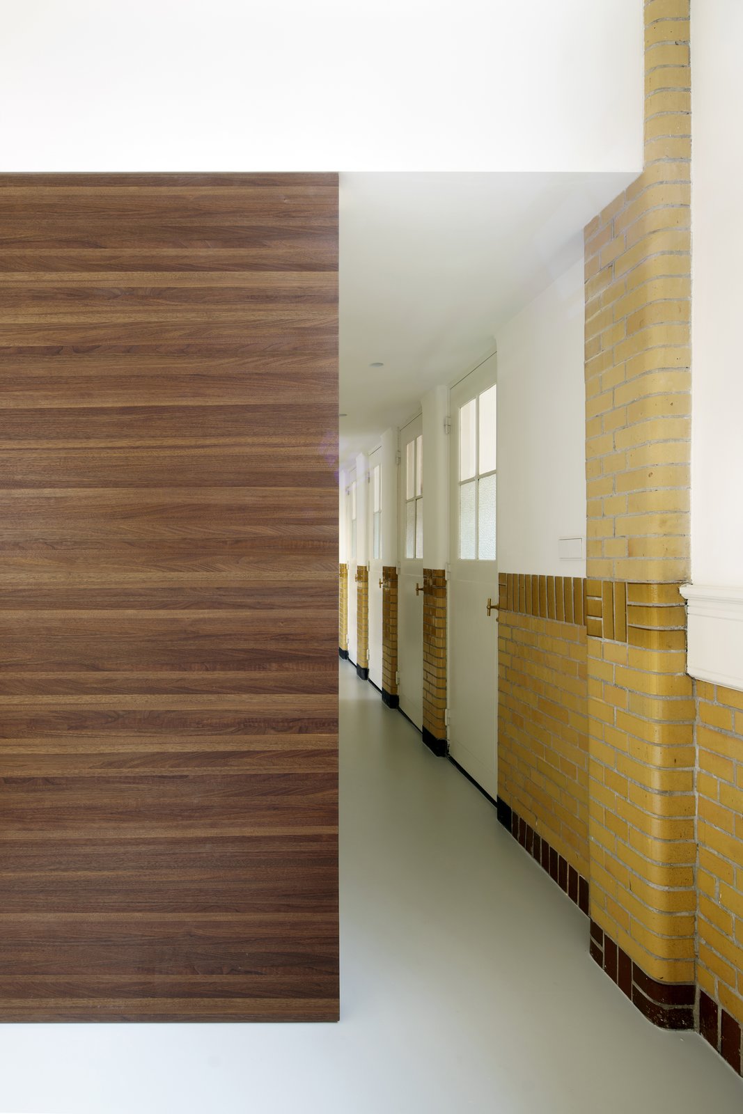 A wooden box, which houses a walk-in-closet and stairs to the bedrooms, acts as a partition that dissects the hallway.
