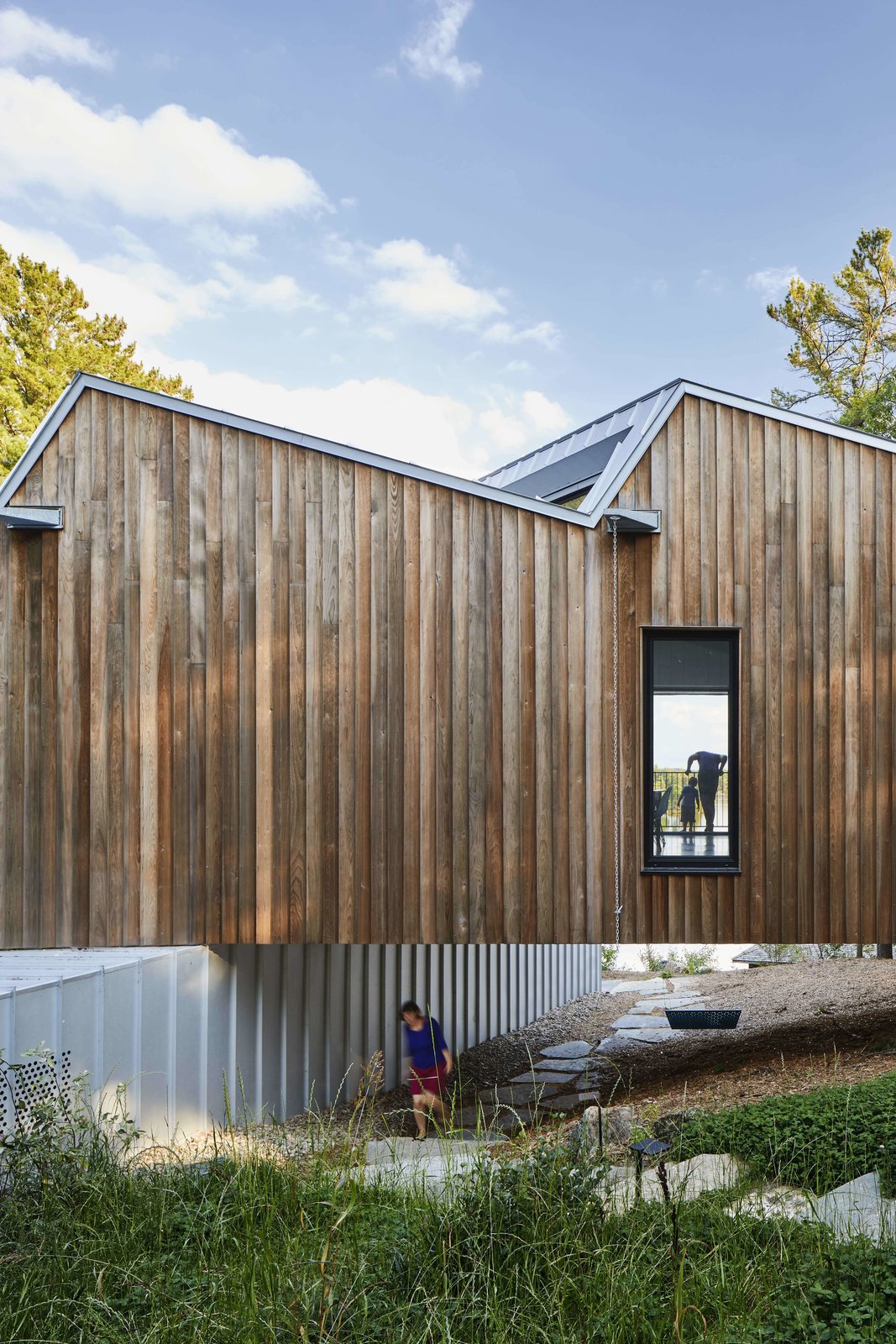 A stone foot path and a custom-made undercroft swing-bench were incorporated into the pocket of space between the ground and the floor of the upper volume.