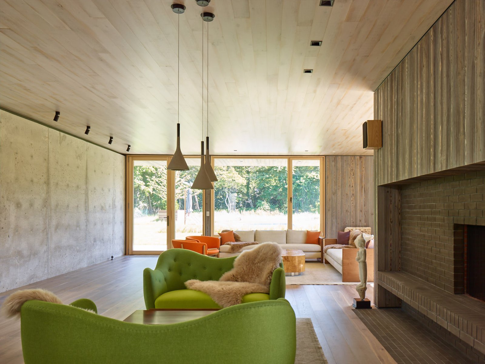 A green Finnjuhl sofa and table at fireplace, and pendants from Foscarini.
