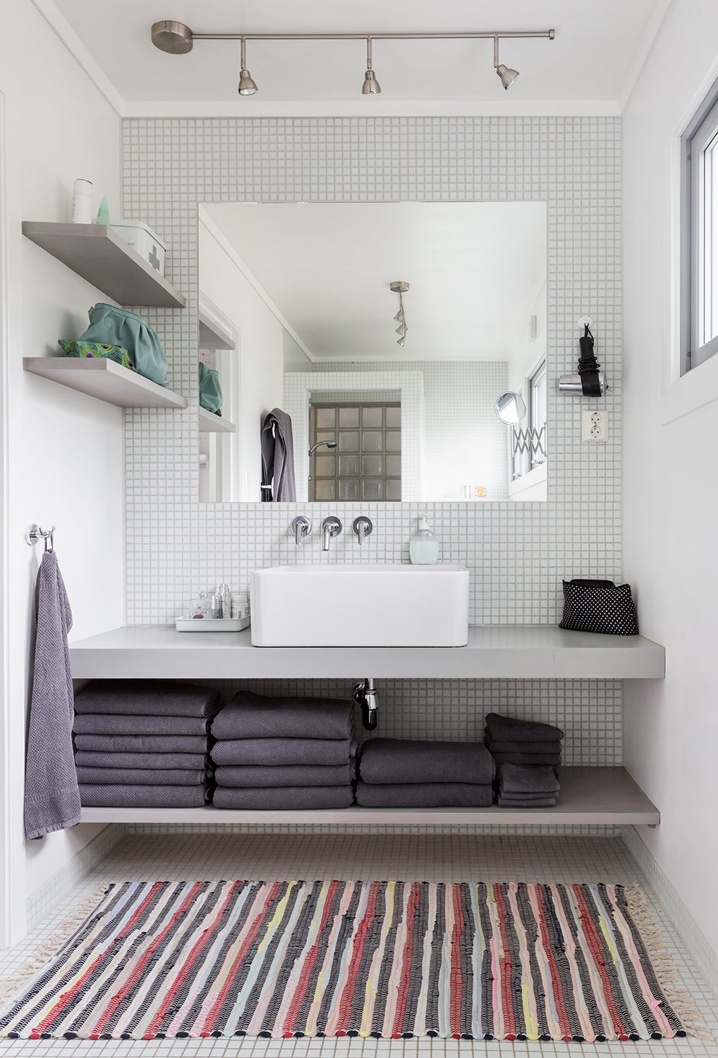 Built-in shelves and an unframed mirror give the bathroom vanity a clean and streamlined look.