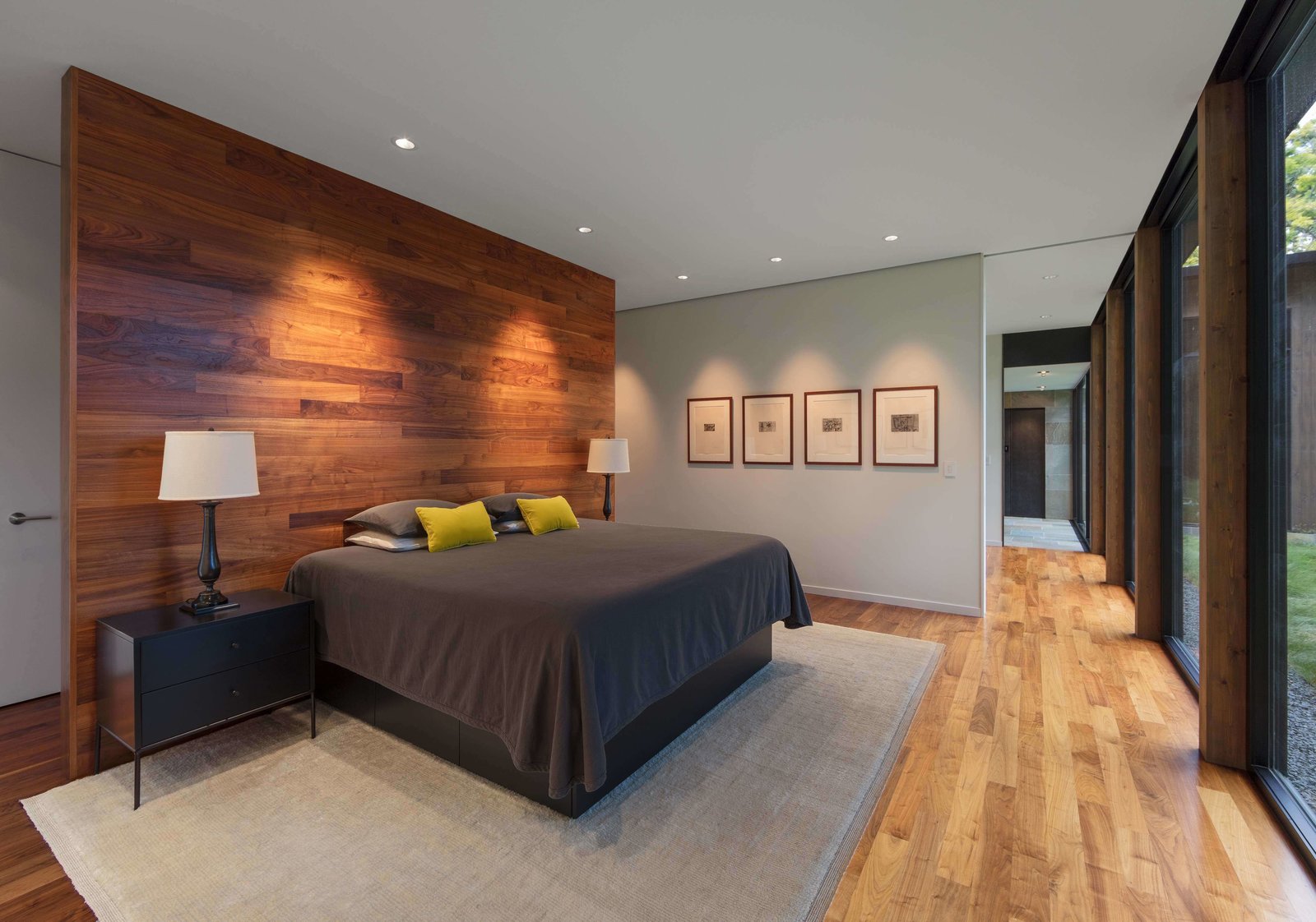 In the master bedroom, a wooden accent wall with coat hooks on one side, serves as a partition for the bed.