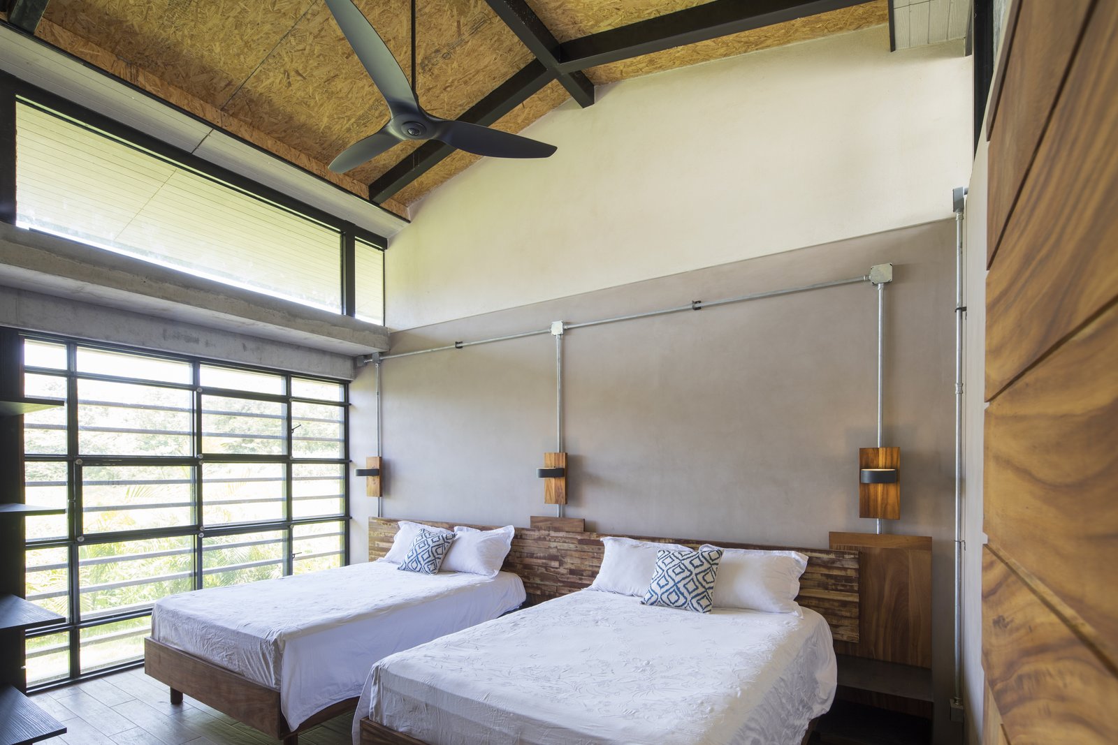 Floor to ceiling glass windows bring the green outdoors into the bedroom.