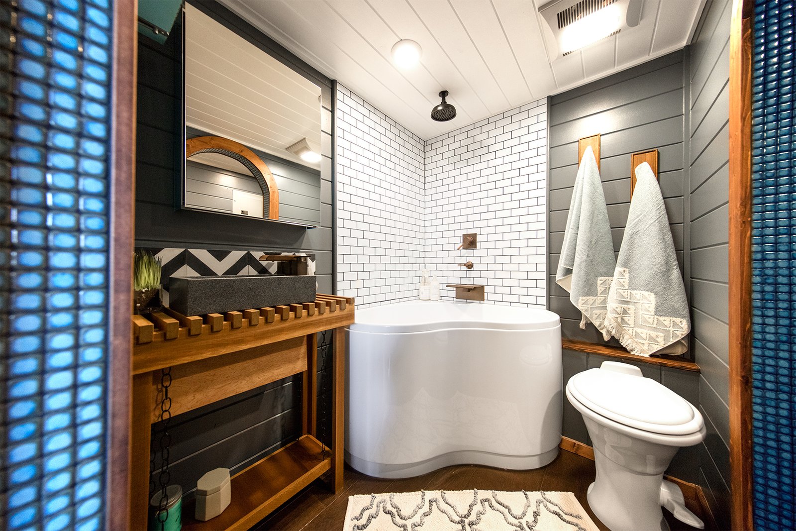 On the opposite end of the dining area is a spa-like bathroom with sliding arched doors, Moroccan tile trimming, a walk-closet, toilet, rain shower, and a corner jacuzzi bathtub.