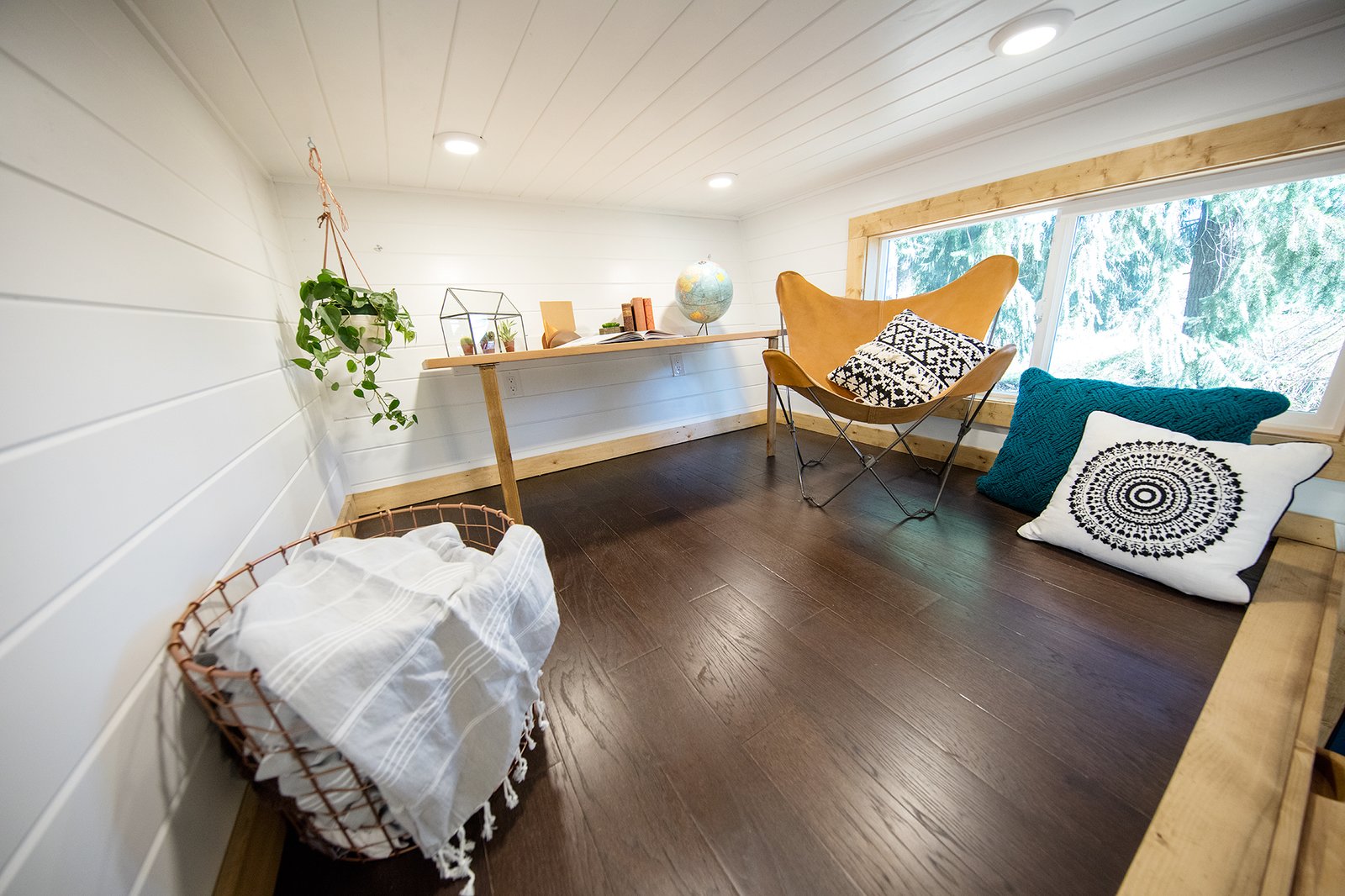 Above the dining area is a lofted lounge and office space with a small desk, chair and cushions.
