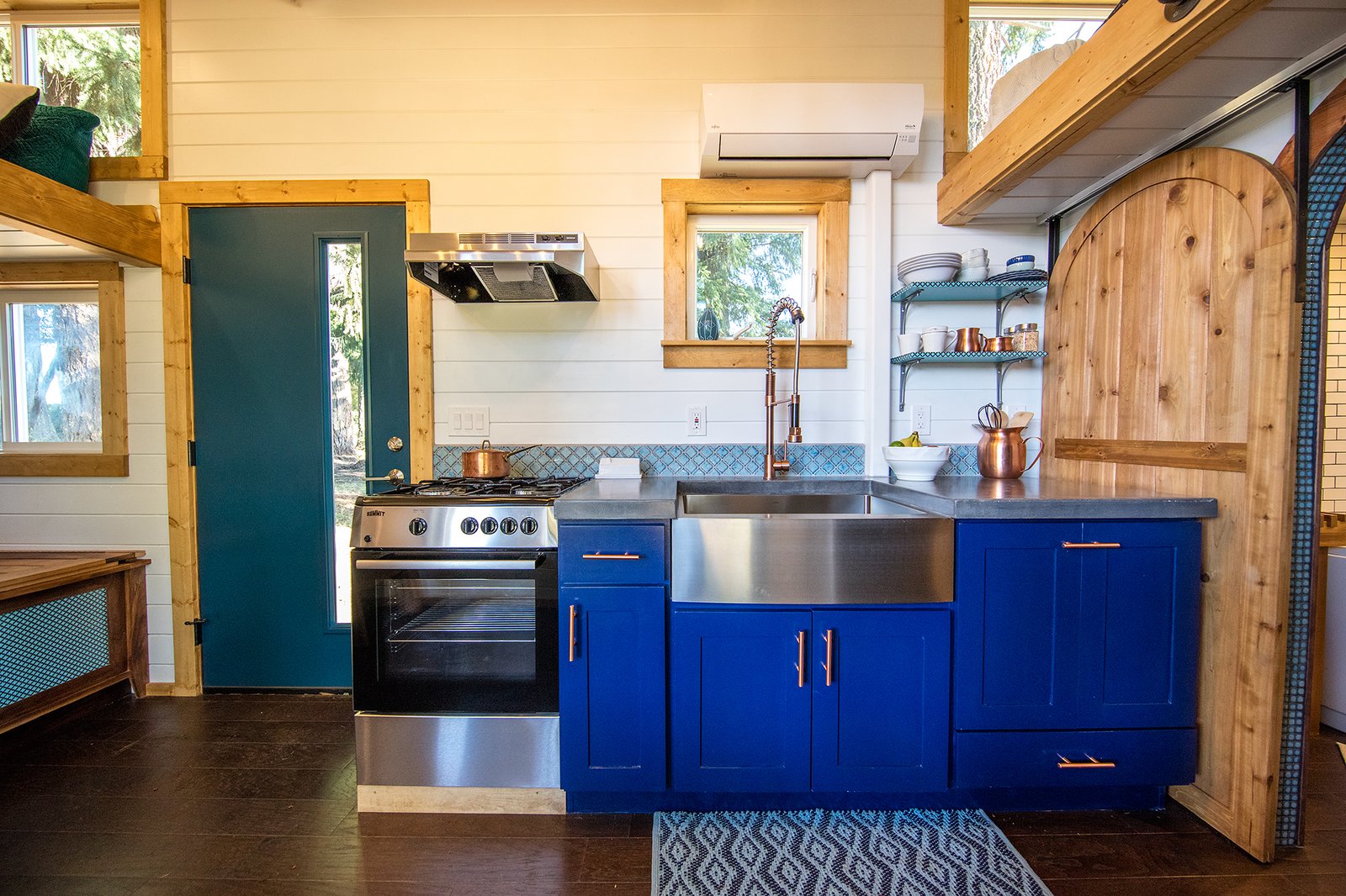 The kitchen has concrete countertops and bright blue cabinets.