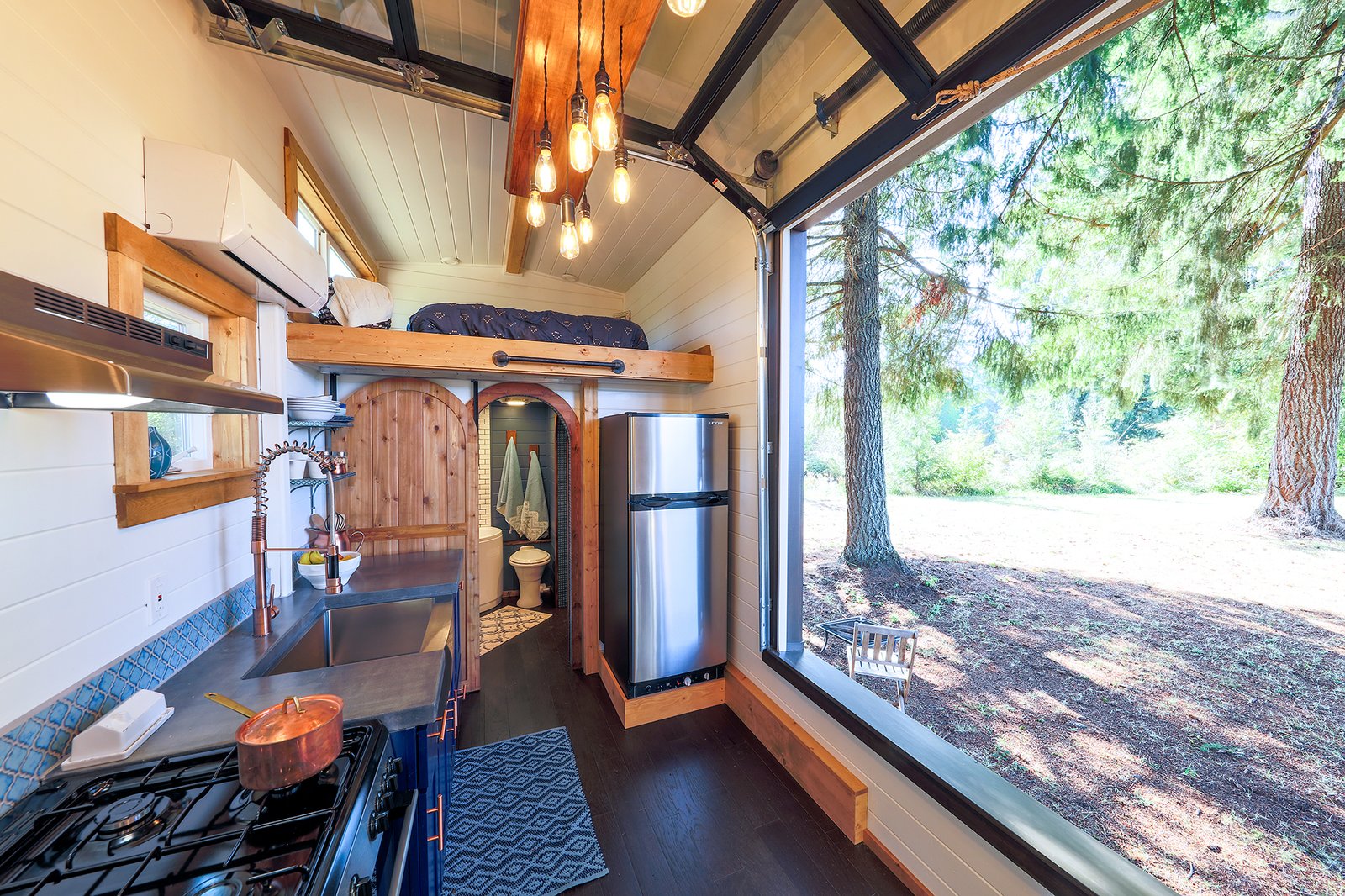 A fully glazed wall frames the natural scenery outdoors, making the house feel much larger than it's actual size.