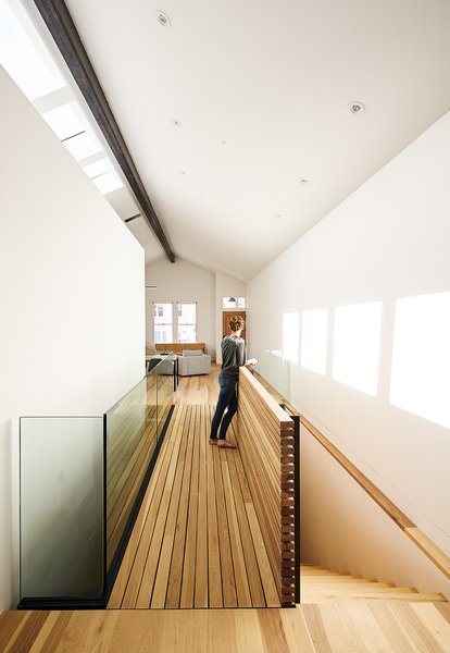 Working with an empty shell due to a fire the designers created a 13-foot ceiling on the main floor, located above street level. Within that they tucked a "house-within-a-house" against the southern wall. The mini-house encloses a guest and powder room. Its "roof" catches the sun that pours in through four skylights above it. A bridge links the living area to the kitchen. Photo of A Renovated Tiny Victorian modern home