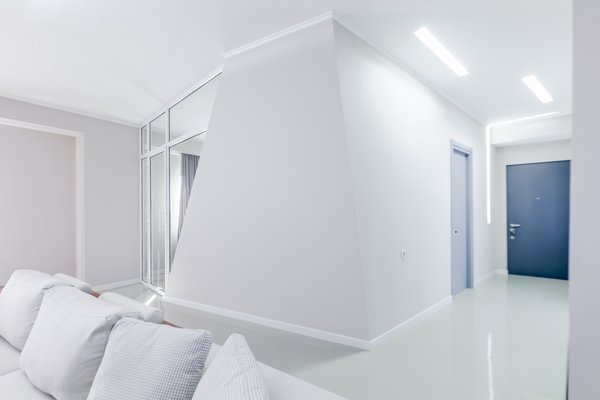 As soon as you enter the space, the core aesthetic of the design unfolds and it is only possible to see the main room through the tilted hallway. It meant to take your time for the idea of an actual comfort, smartness and practicality of the design to sink in. When navigating further into the room, one realizes, that the slopes direct the visitor from the narrow spaces toward the wider ones and vice versa. Leaning walls bend the space, making it simultaneously modest and sharp.
The intention of diagonal walls being directional carries through the bedroom as well, but here, the steepness accentuates the workstation. In the case of the bathroom, the slope serves as a surface to lean on and relax. Photo 13 of Cave modern home