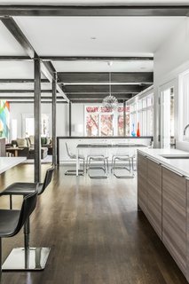 12 Modern Marvels in New England - Photo 4 of 12 - Double islands and durable modern finishes make the kitchen a cook’s dream, especially for an active young family. As the kitchen tends to be a space where people congregate, the double islands and expansive layout are ideal for hosting. Exposed steel beams continue from the kitchen through the breakfast and bar area into the family room and terminate at the bold, wallpaper accented back wall. 