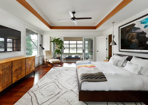 Modern home with hardscapes, back yard, large patio, porch, deck, landscape lighting, ceiling lighting, recessed lighting, sectional, coffee tables, metal fence, ottomans, table, accent lighting, stools, wood patio, porch, deck, decking patio, porch, deck, dresser, undermount sink, two piece toilet, chair, and gas burning fireplace. The Master bedroom featuring a burl wood cabinet by Romweber, custom platform bed, early Milo Baughman chair and ottoman by James Co., opening to the screened porch featuring Restoration Hardware's Costa Luxe double lounger. Over the bed is an original print of David Drebin's Looking Down flanked by a pair of vintage Jo Hammerborg pendant lights. The rug is Moroccan from Black Sheep Unique in Austin, TX. Photo 16 of Lake Austin Remodel