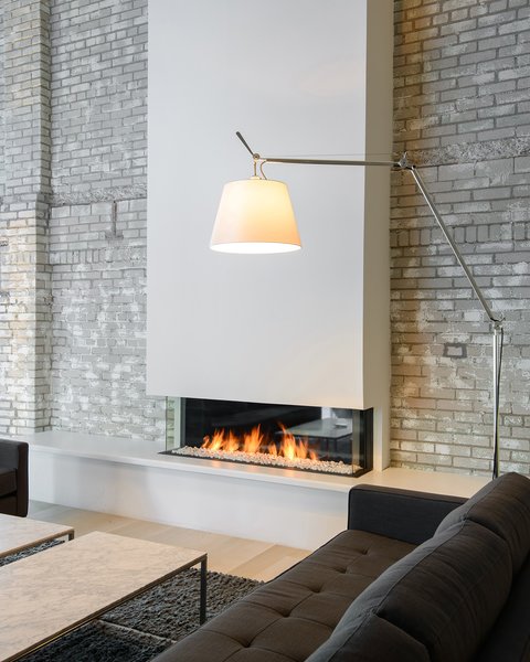 Modern home with living room and office. Re-Imagining Space
If you can imagine, this cozy, hygge-filled space was once an old drafty elevator shaft and mechanical room, according to designer Kar-Keat Chong. He hoped to re-invent a space where the employees could “break away” from the open office environment down below. This is a place that offers a more casual and comfortable zone. He said that the fireplace serves to anchor the space as a “central highlight and focal point.” Photo 2 of Mithun Agency