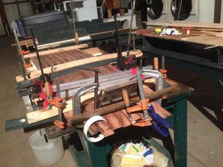 Crafting a Hollow Wood Surfboard from Old-Growth Redwood - Photo 10 of 26 - Clamping the deck and bottom to the skeleton by all means necessary—threaded rods, G-clamps, strips of PVC pipe, and later, those water bins on top.